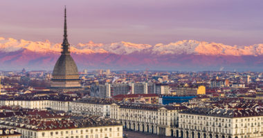 Torino (Turin, Italy): cityscape at sunrise with details of the Mole Antonelliana towering over the city. Scenic colorful light on the snowcapped Alps in the background.