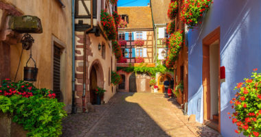 Narrow street and beautiful historic houses in old part of Riquewihr village, wine route in Alsace region, France