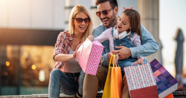 Happy family with shopping bags.Family shopping.Young parents and their daughter are carrying shopping bags.Happy family with shopping bags resting after shopping.